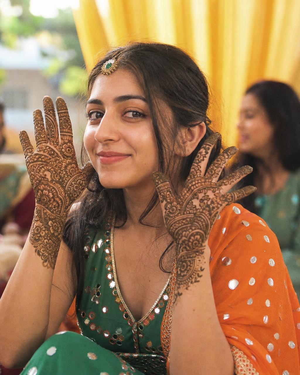Bride with mehendi ceremony makeup and henna on her hands