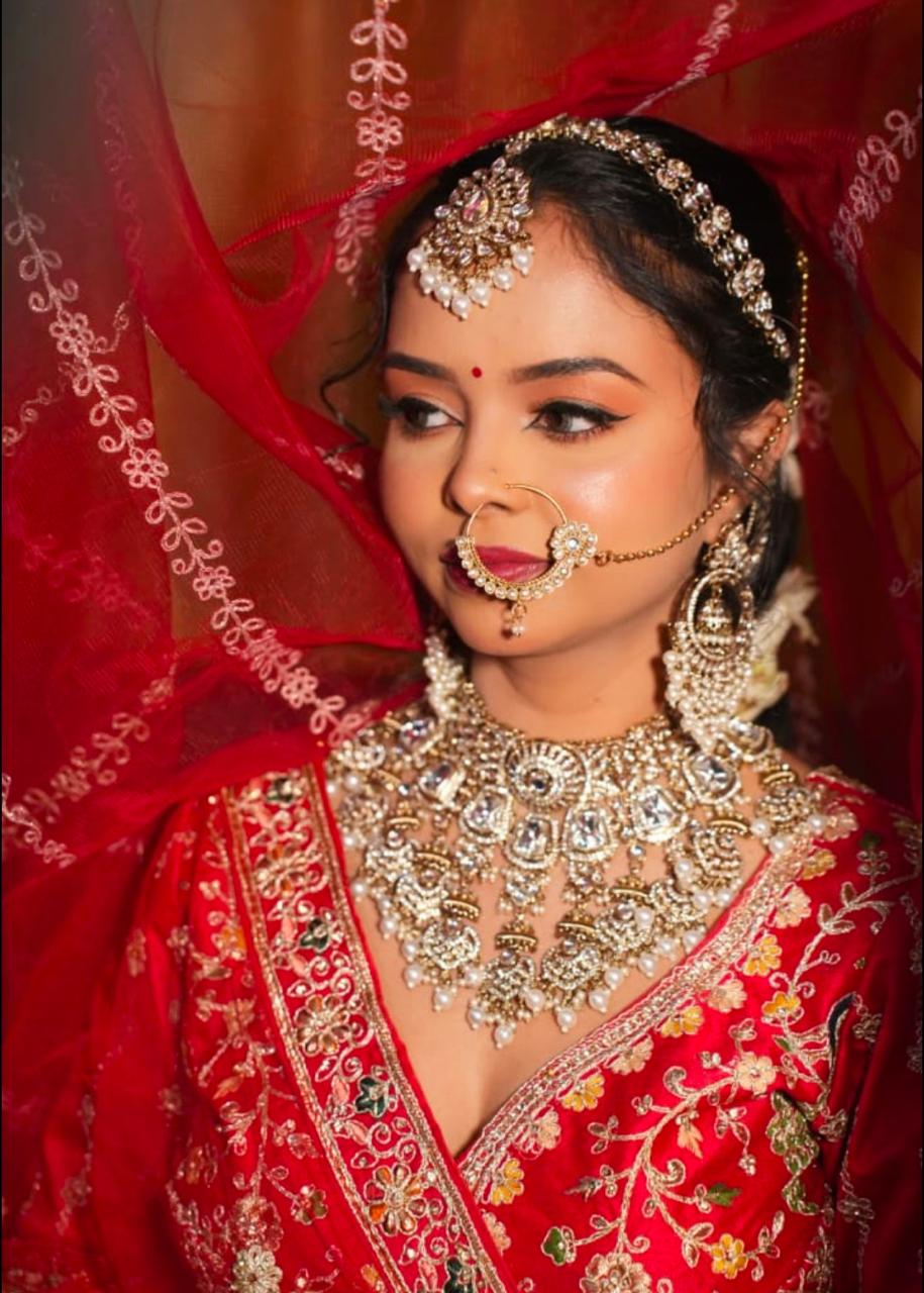Bride in a red and gold lehenga with HD bridal makeup by Aakanksha Makeovers, Patna