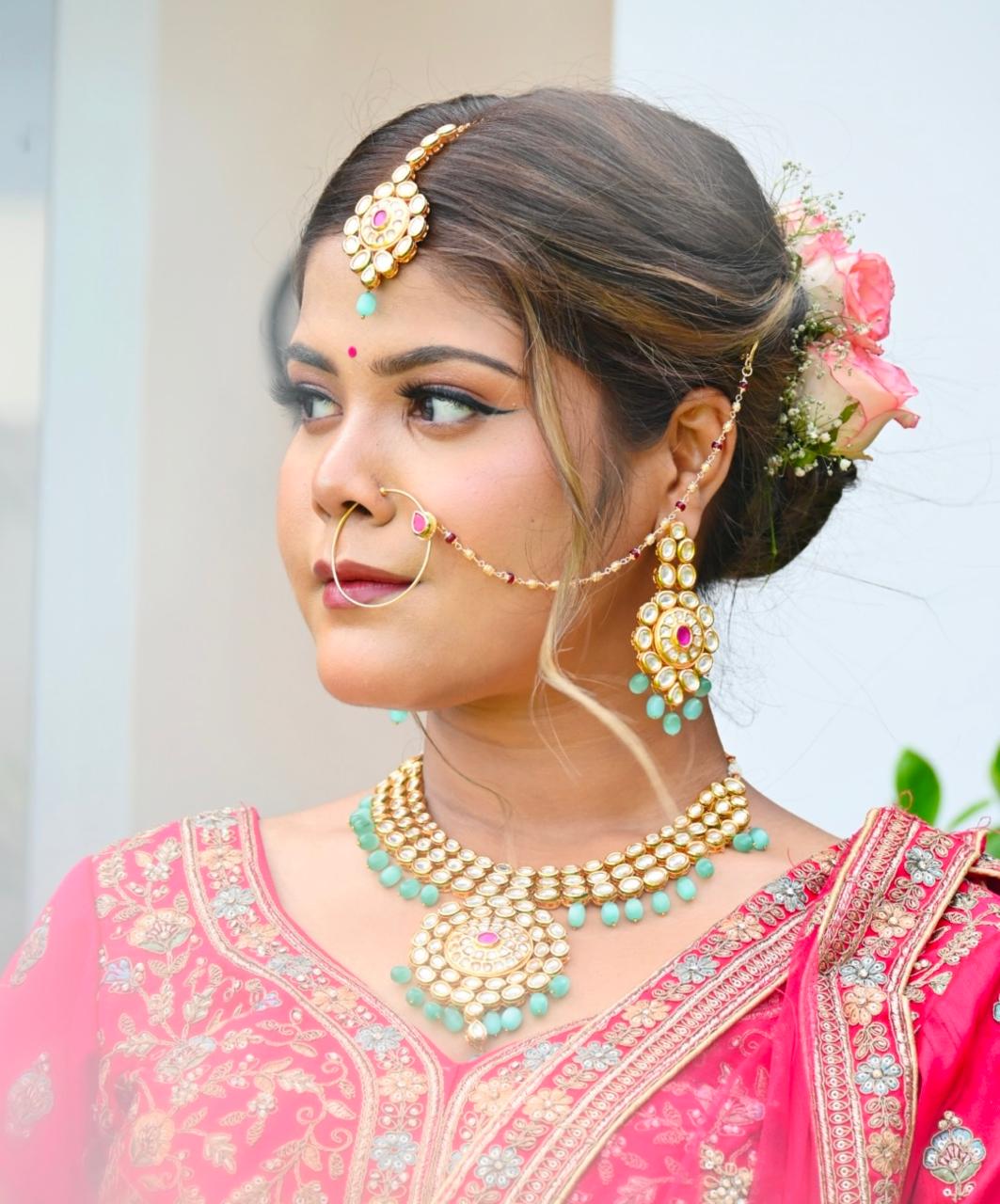 Bride with reception makeup in a pink outfit and gold jewellery